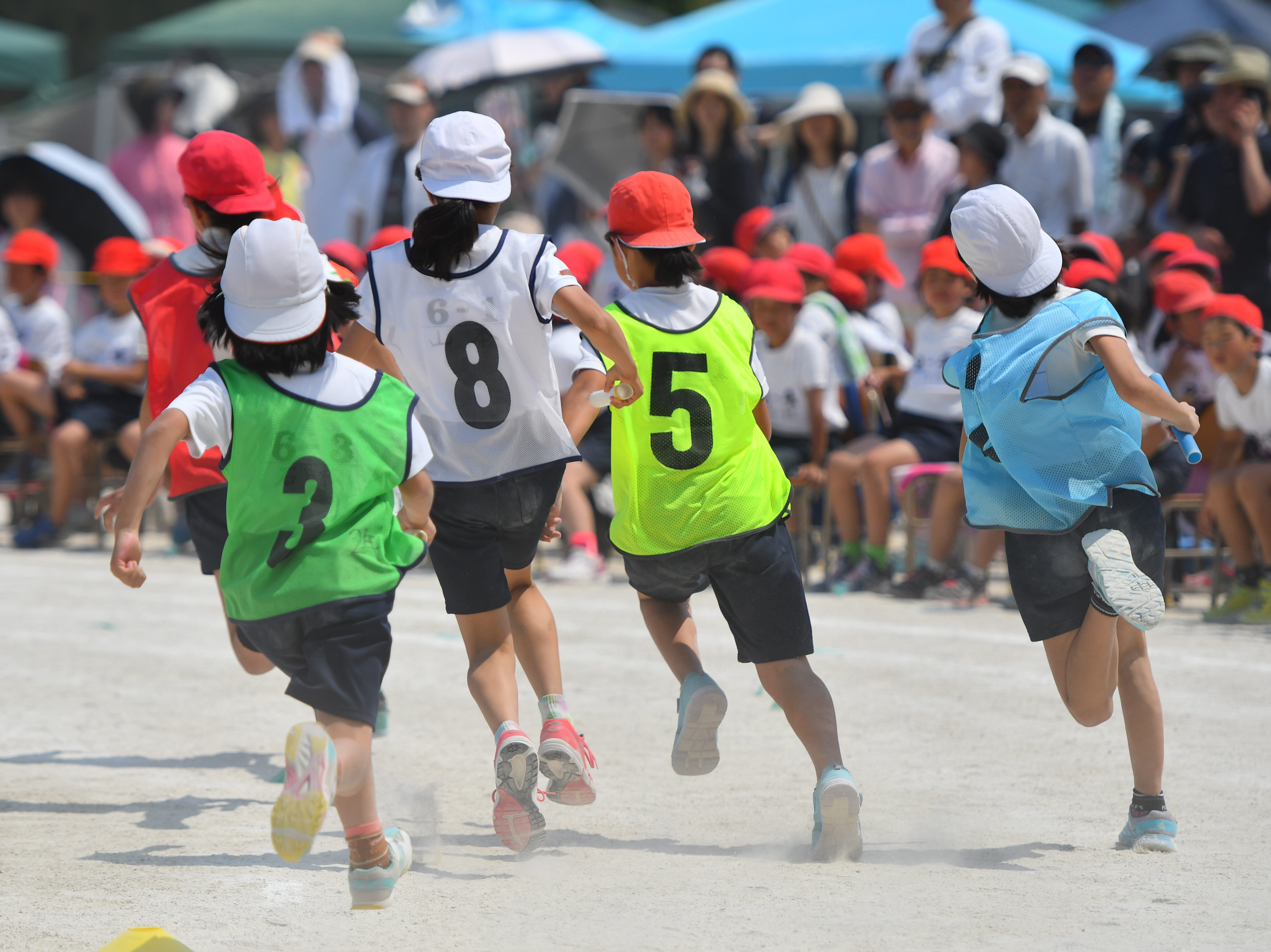 小学校の運動会のリレーで走る子供たち